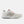A white New Balance athletic shoe shown from the side profile against a light gray background. The shoe features a white mesh upper, a prominent gray 'N' logo outlined in black, a white midsole, and small orange accents near the laces and heel.