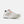 A white New Balance athletic shoe with a black outlined 'N' logo, white laces, and bright orange accents on the tongue and lace loop, shown against a light gray background.
