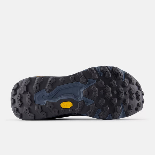 Close-up of the outsole of a New Balance outsole with textured pattern and yellow accent on a light gray background