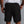 Person wearing black shorts with a small logo on a gray background