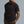 Man wearing a black t-shirt with a brand logo on a gray background