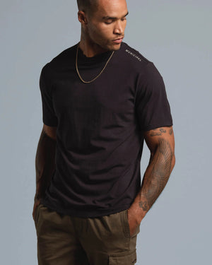Man wearing a black t-shirt with a brand logo on a gray background