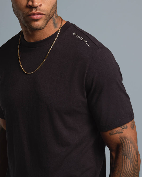 Man wearing a black t-shirt with 'Municipal' logo on a gray background