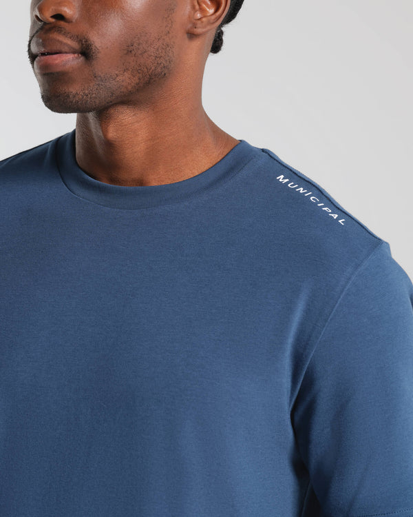 Man wearing a blue t-shirt with 'Municipal' logo on a gray background