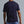 Man wearing a navy blue t-shirt and light blue pants against a gray background