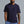 Man wearing a navy blue t-shirt and blue shorts against a gray background