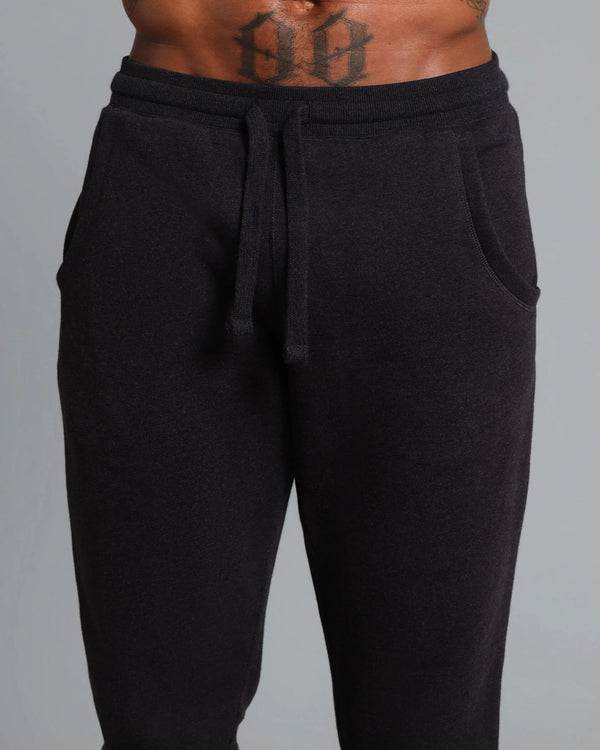 Black sweatpants worn by a person on a gray background