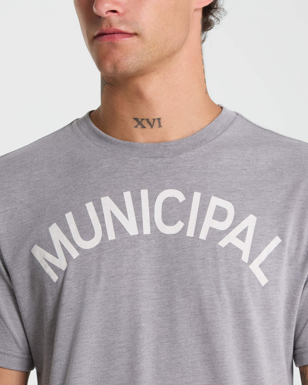 Gray t-shirt with 'MUNICIPAL' text worn by a person on a white background