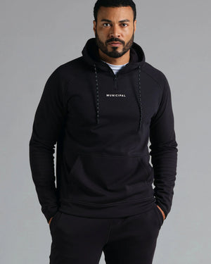 Man wearing a black hoodie with 'MUNICIPAL' text on a gray background