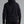 Person wearing a black hoodie and pants on a gray background