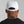 Person wearing a white cap with tattoos visible on the back of their neck against a gray background.