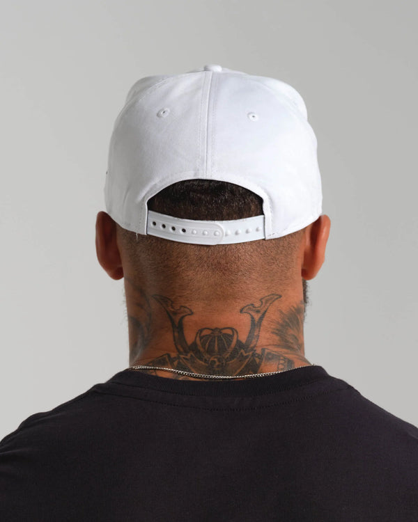 Person wearing a white cap with tattoos visible on the back of their neck against a gray background.