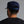 Person wearing a navy blue cap with a logo on the back against a gray background