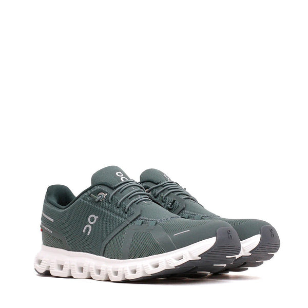 Green running shoes with white sole on a white background