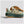 Green and brown sneaker with New Balance logo on a light gray background