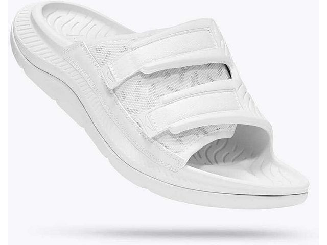 Lateral angled view of the Unisex Ora Luxe Recovery Slide by HOKA in the color white